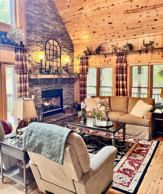 living room featuring wooden walls, wood-type flooring, a fireplace, and high vaulted ceiling