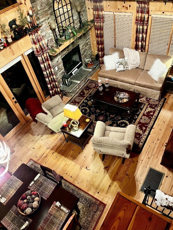 living room featuring wood-type flooring and a stone fireplace