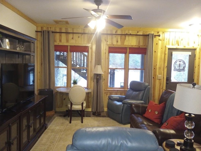 sitting room with ceiling fan and wood walls