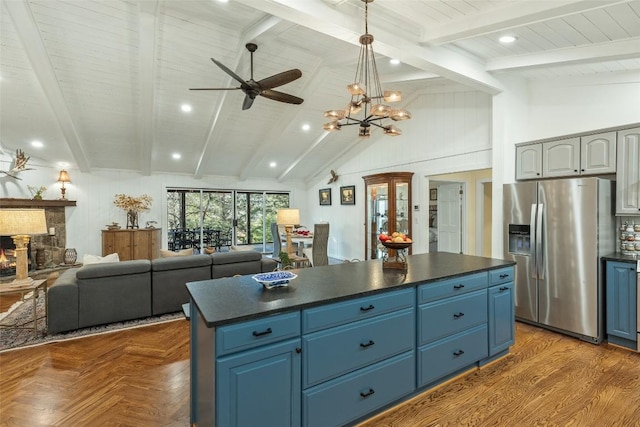 kitchen featuring blue cabinetry, a kitchen island, dark countertops, a fireplace, and stainless steel fridge with ice dispenser