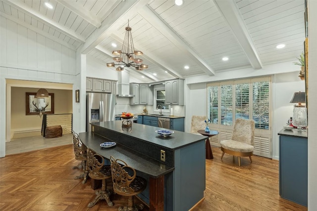 kitchen with stainless steel appliances, beam ceiling, dark countertops, and gray cabinets