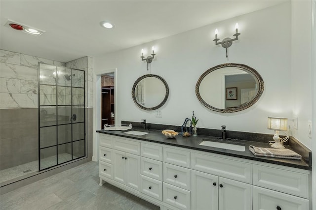 bathroom with a sink, recessed lighting, double vanity, and a tile shower