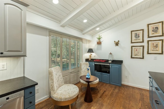 kitchen with dark countertops, blue cabinetry, dark wood finished floors, lofted ceiling with beams, and stainless steel dishwasher