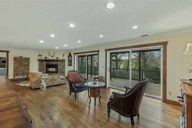 living room with wood finished floors, a fireplace, visible vents, and ornamental molding