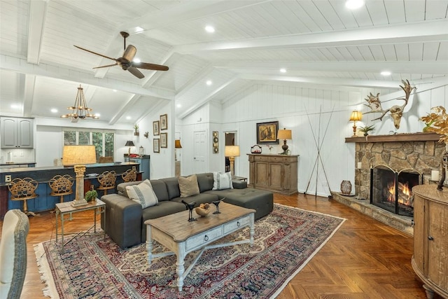 living area featuring a stone fireplace, ceiling fan with notable chandelier, and vaulted ceiling with beams