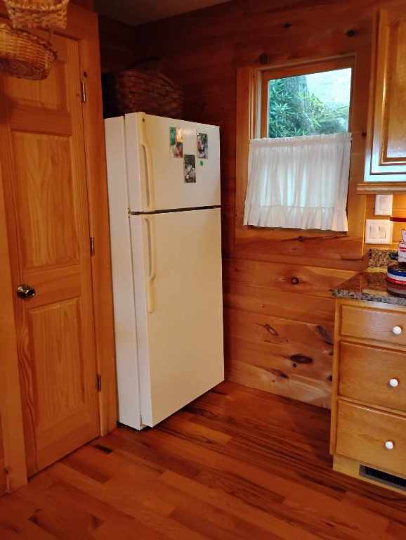 172 Moon Ridge Dr, Sky Valley, GA 30537 - kitchen featuring freestanding refrigerator, wood finished floors, wooden walls, and dark stone counters