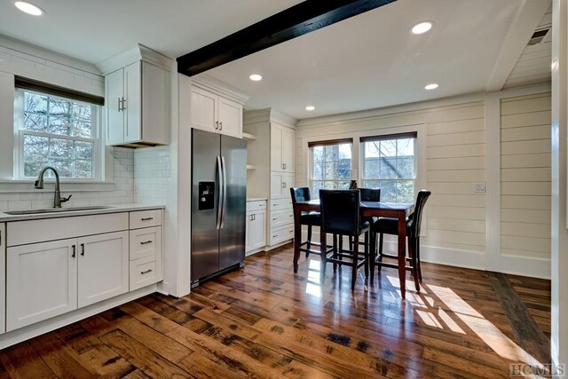 kitchen featuring sink, white cabinetry, stainless steel fridge with ice dispenser, dark hardwood / wood-style flooring, and beam ceiling