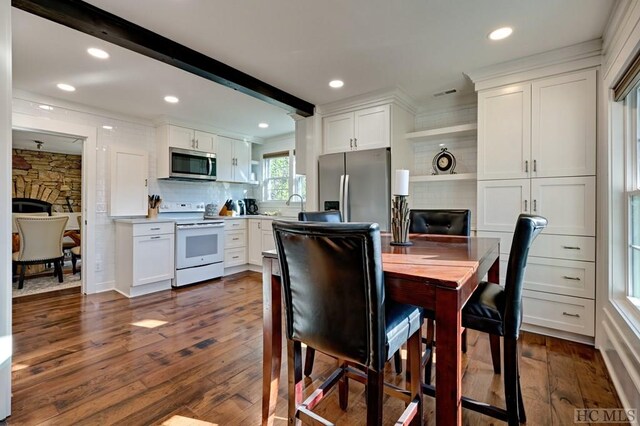 kitchen with beam ceiling, dark hardwood / wood-style floors, white cabinets, and appliances with stainless steel finishes