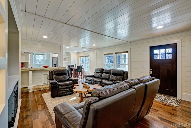 living room with wooden walls, sink, wood ceiling, and light hardwood / wood-style floors