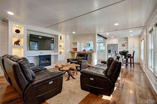 living room featuring hardwood / wood-style floors, wooden ceiling, and sink