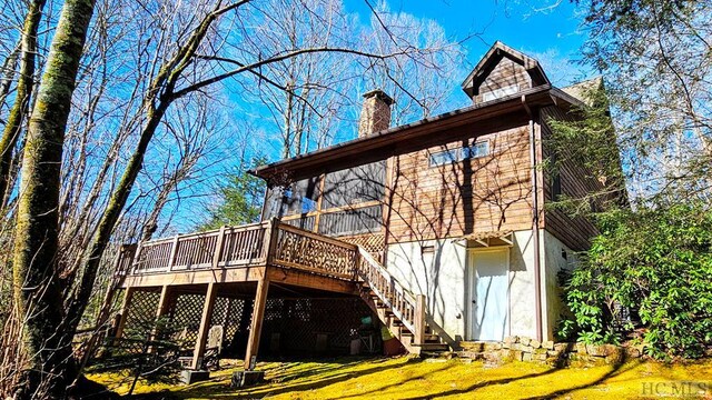 back of property with a deck and a lawn