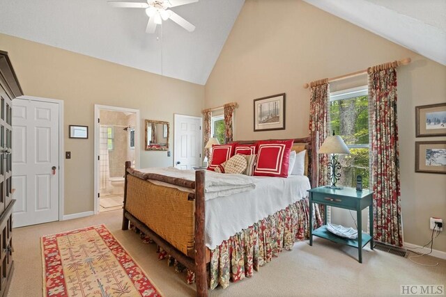 bedroom featuring ceiling fan, high vaulted ceiling, light carpet, and ensuite bath