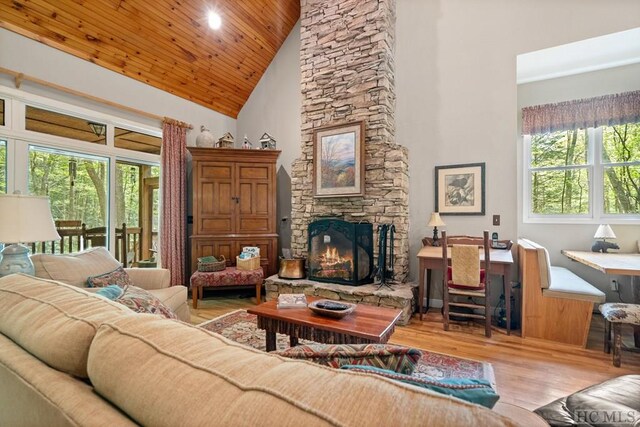 living room featuring high vaulted ceiling, light hardwood / wood-style flooring, a fireplace, and wooden ceiling