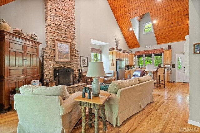 living room featuring high vaulted ceiling, light hardwood / wood-style flooring, wood ceiling, and a fireplace