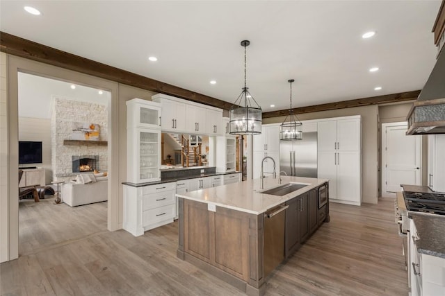 494 E Ridge Rd, Cashiers, NC 28717 - kitchen with built in appliances, a sink, an island with sink, light wood-type flooring, and a stone fireplace