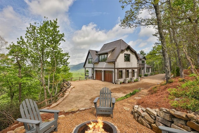 494 E Ridge Rd, Cashiers, NC 28717 - back of property featuring an outdoor fire pit, concrete driveway, metal roof, and a garage
