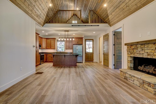 kitchen featuring hanging light fixtures, a kitchen island, appliances with stainless steel finishes, and high vaulted ceiling