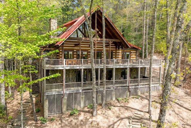 back of house featuring a wooded view and a chimney