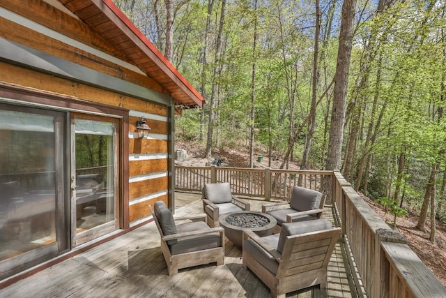 wooden deck featuring a fire pit and a forest view
