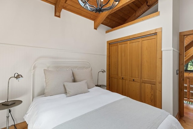 bedroom with wood ceiling, a chandelier, wainscoting, wood finished floors, and a closet
