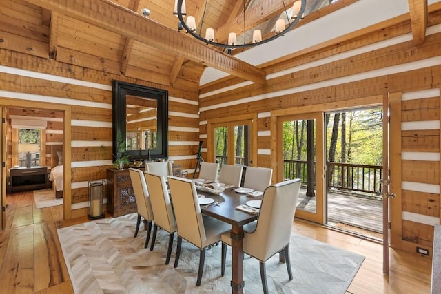 dining room featuring high vaulted ceiling, healthy amount of natural light, wooden walls, light wood-style floors, and beamed ceiling