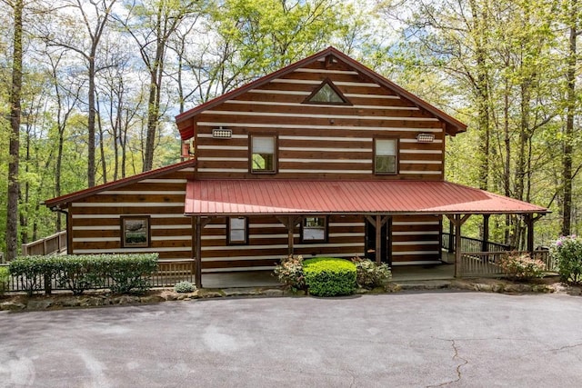 log cabin with a porch and metal roof