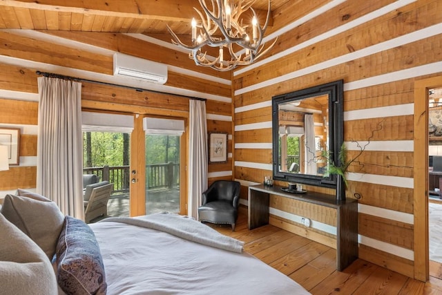 bedroom featuring a chandelier, access to exterior, a wall mounted AC, hardwood / wood-style flooring, and wooden walls