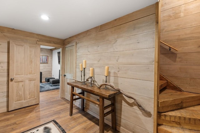hallway with wood finished floors, wooden walls, and recessed lighting