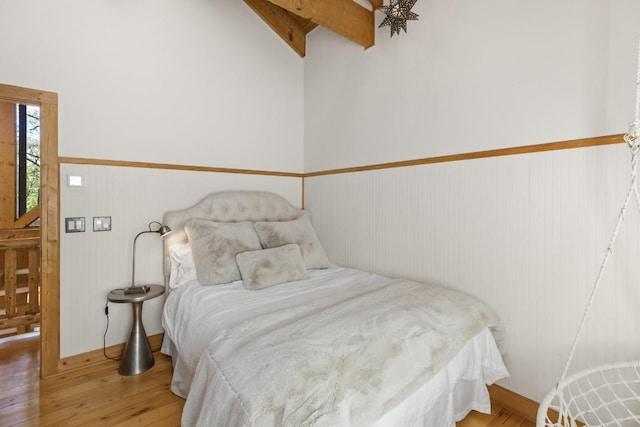 bedroom featuring hardwood / wood-style flooring, a wainscoted wall, and lofted ceiling