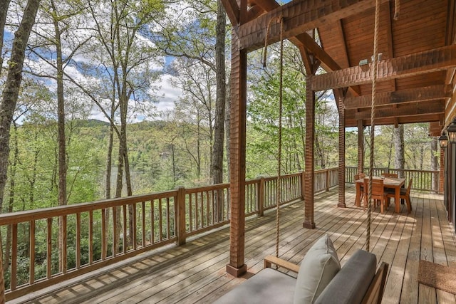 wooden deck with outdoor dining space and a view of trees