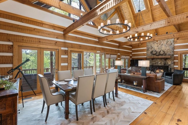 dining area with wood walls, a chandelier, beam ceiling, healthy amount of natural light, and high vaulted ceiling