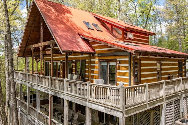 rear view of property featuring metal roof, a deck, and log exterior