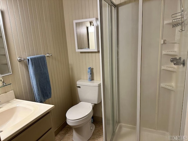 bathroom featuring wooden walls, vanity, tile patterned floors, toilet, and walk in shower