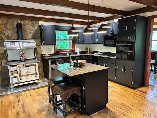 kitchen featuring light hardwood / wood-style flooring, hanging light fixtures, a kitchen island, beamed ceiling, and black appliances