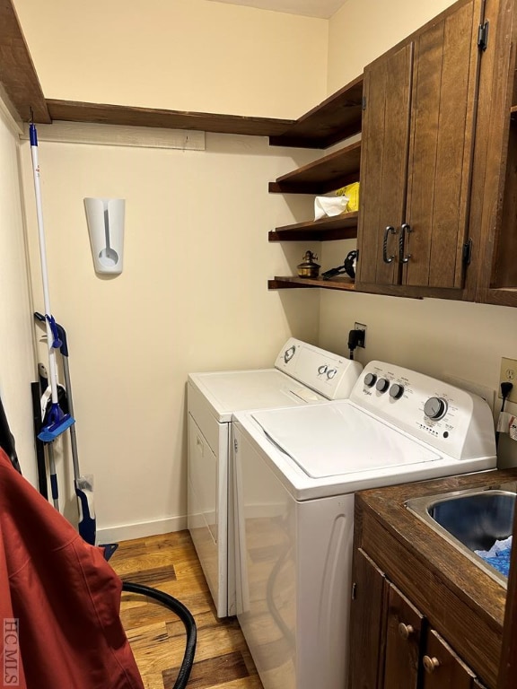 laundry room with cabinets, washer and dryer, and light hardwood / wood-style flooring