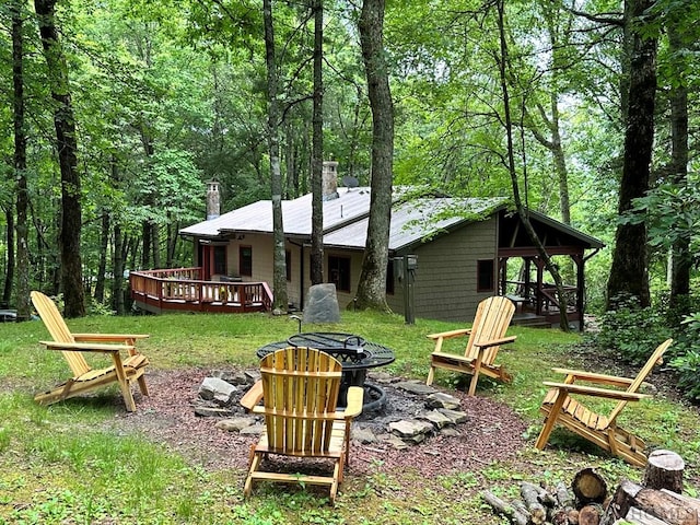 rear view of house with a wooden deck and an outdoor fire pit