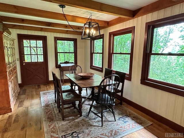 dining room with beamed ceiling, hardwood / wood-style floors, and a notable chandelier