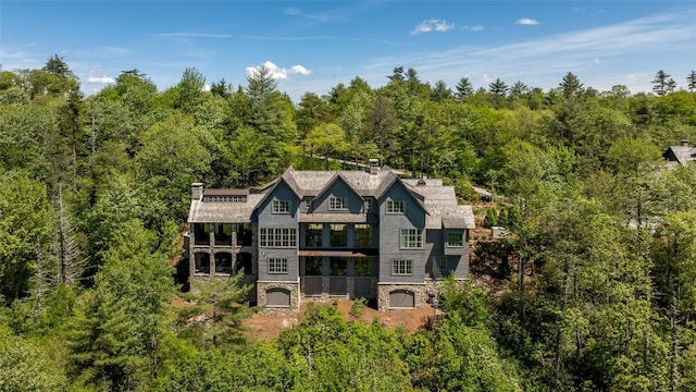 893 High Mountain Dr, Cashiers, NC 28717 - rear view of house with stone siding, a wooded view, a balcony, and a chimney