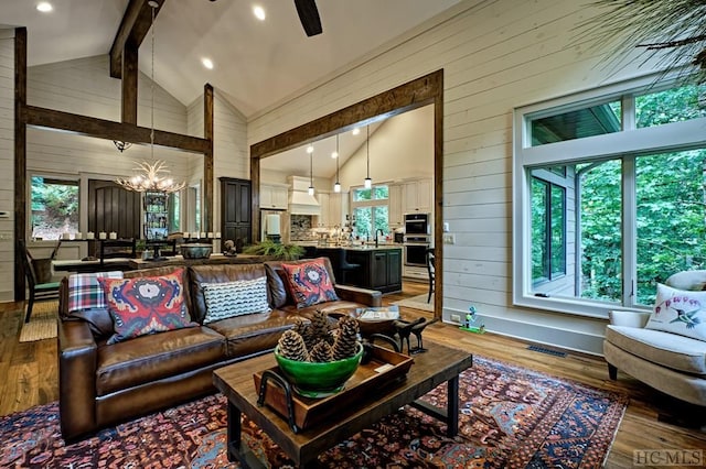 living room featuring wooden walls, light hardwood / wood-style floors, beam ceiling, and a wealth of natural light