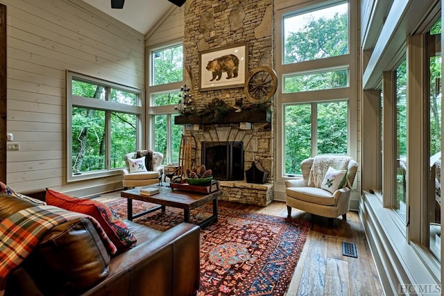 sunroom featuring lofted ceiling, a stone fireplace, and ceiling fan