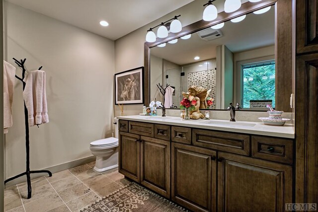 bathroom with vanity, toilet, and a tile shower