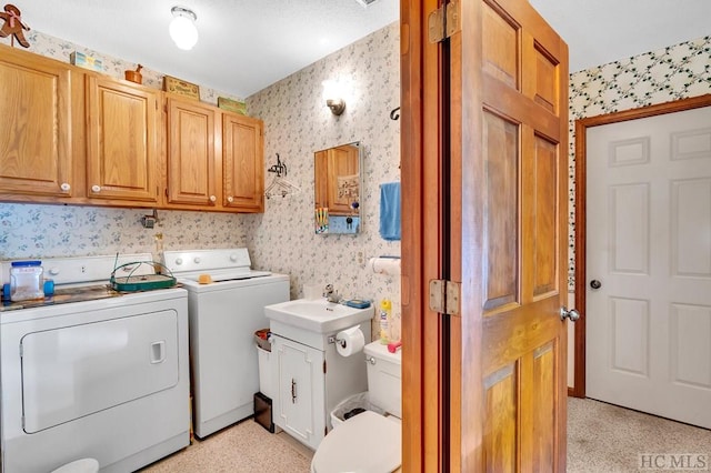 laundry area with cabinets, washing machine and clothes dryer, and sink