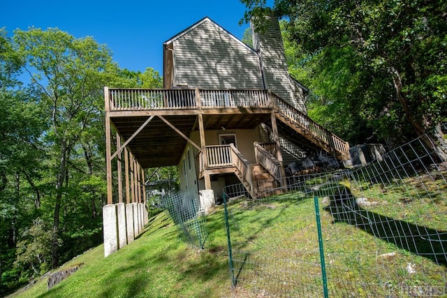 rear view of house with a wooden deck and a lawn