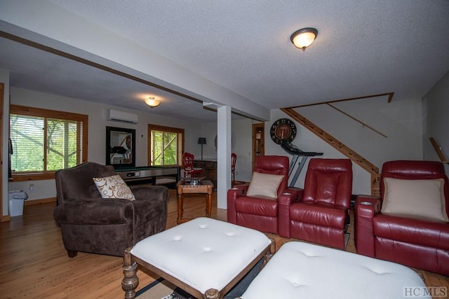 home theater with plenty of natural light, hardwood / wood-style floors, a textured ceiling, and a wall mounted air conditioner