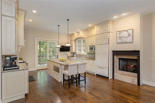 115 Falls Ct W, Highlands, NC 28741 - kitchen featuring stainless steel microwave, dark wood-style floors, a center island, light stone countertops, and a warming drawer