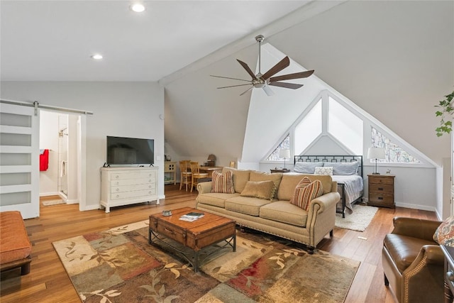 living room with lofted ceiling with beams, wood-type flooring, and a barn door