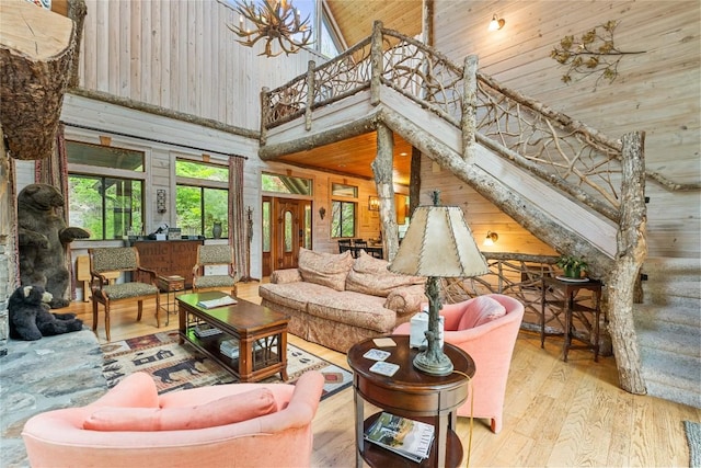 living room featuring a high ceiling, wooden walls, wood ceiling, and light hardwood / wood-style floors