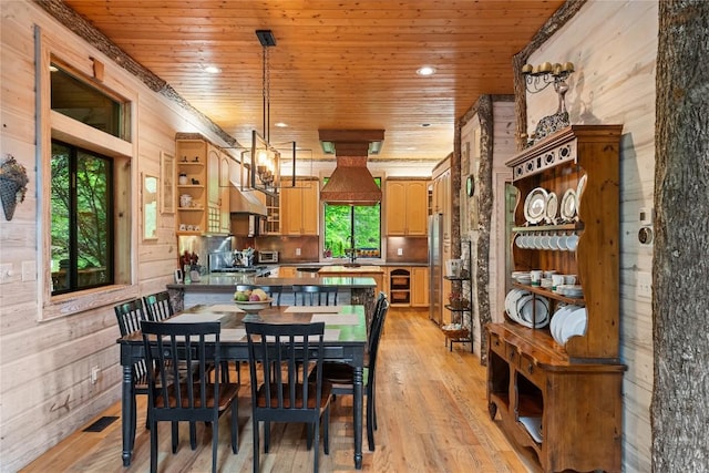 dining room featuring wooden walls, an inviting chandelier, wooden ceiling, and light hardwood / wood-style floors