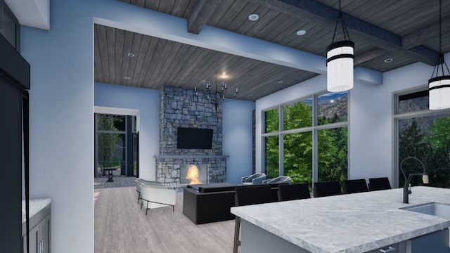 kitchen featuring light wood finished floors, beam ceiling, a fireplace, a sink, and wooden ceiling