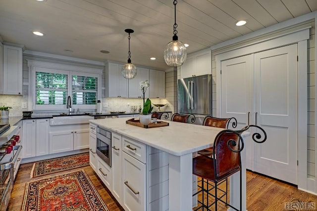 kitchen with a kitchen breakfast bar, appliances with stainless steel finishes, white cabinetry, and a center island